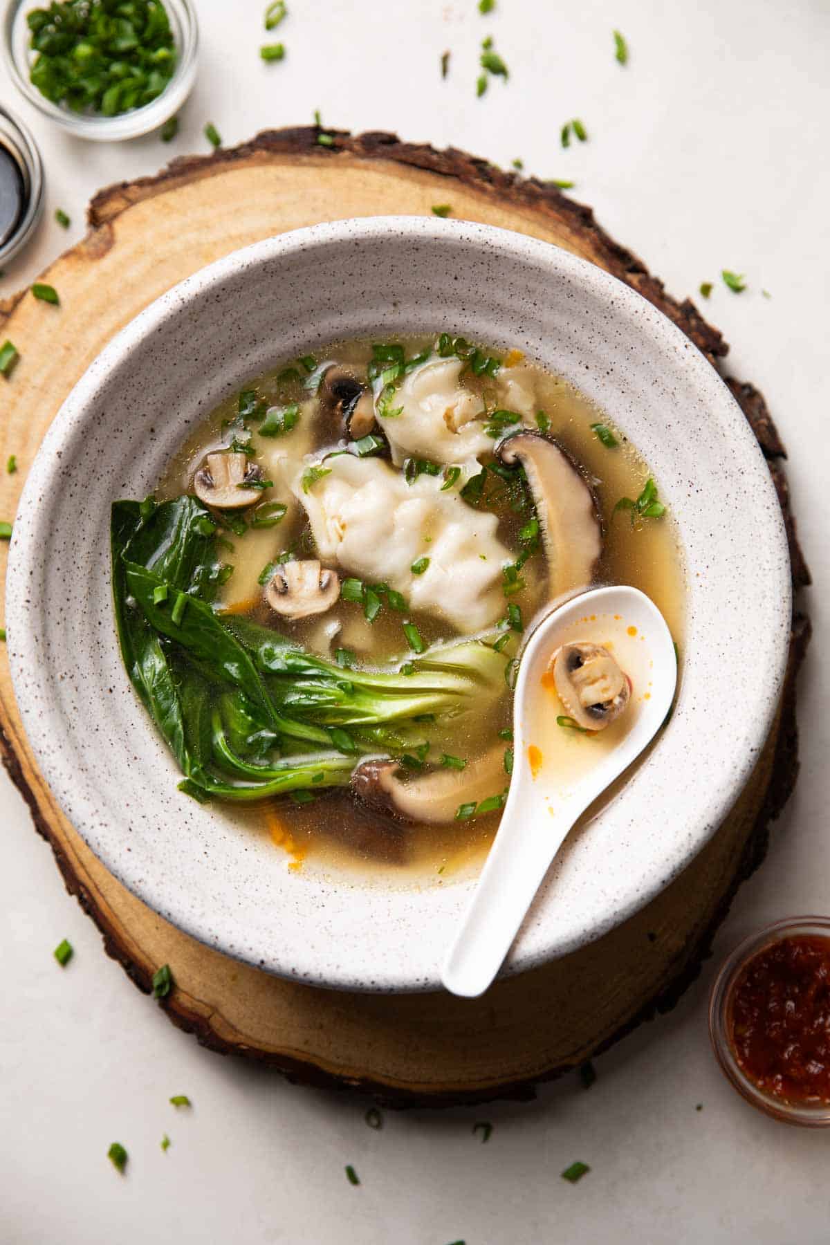 Wanton soup served in a white bowl with spoon