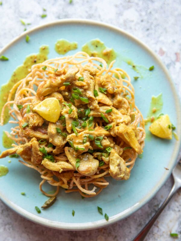 lemon chicken served on a bed of fried noodles on a blue plate with fork