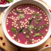 anar pani puri garnished with coriander leaves and boondi and served in a white bowl
