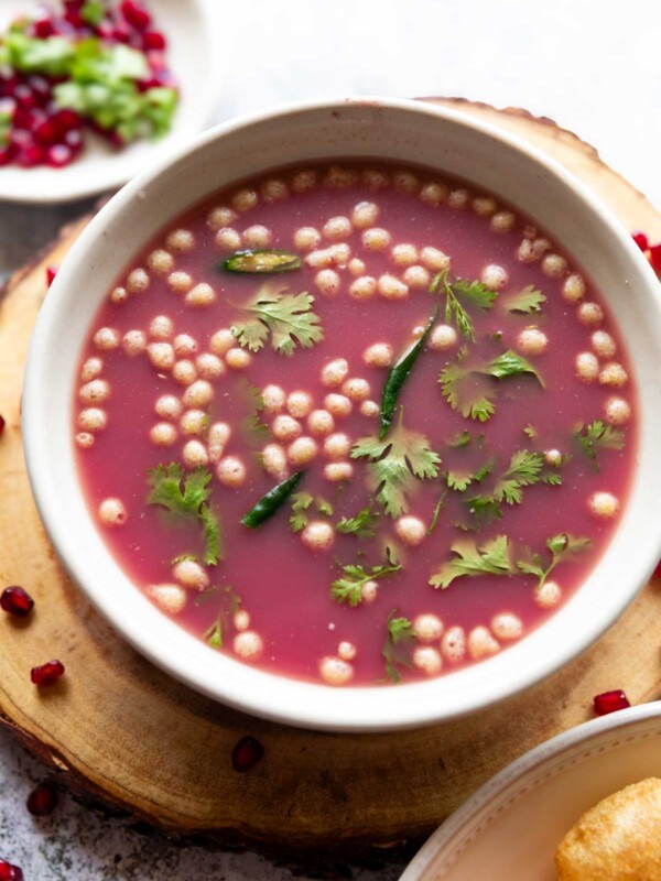 anar pani puri garnished with coriander leaves and boondi and served in a white bowl