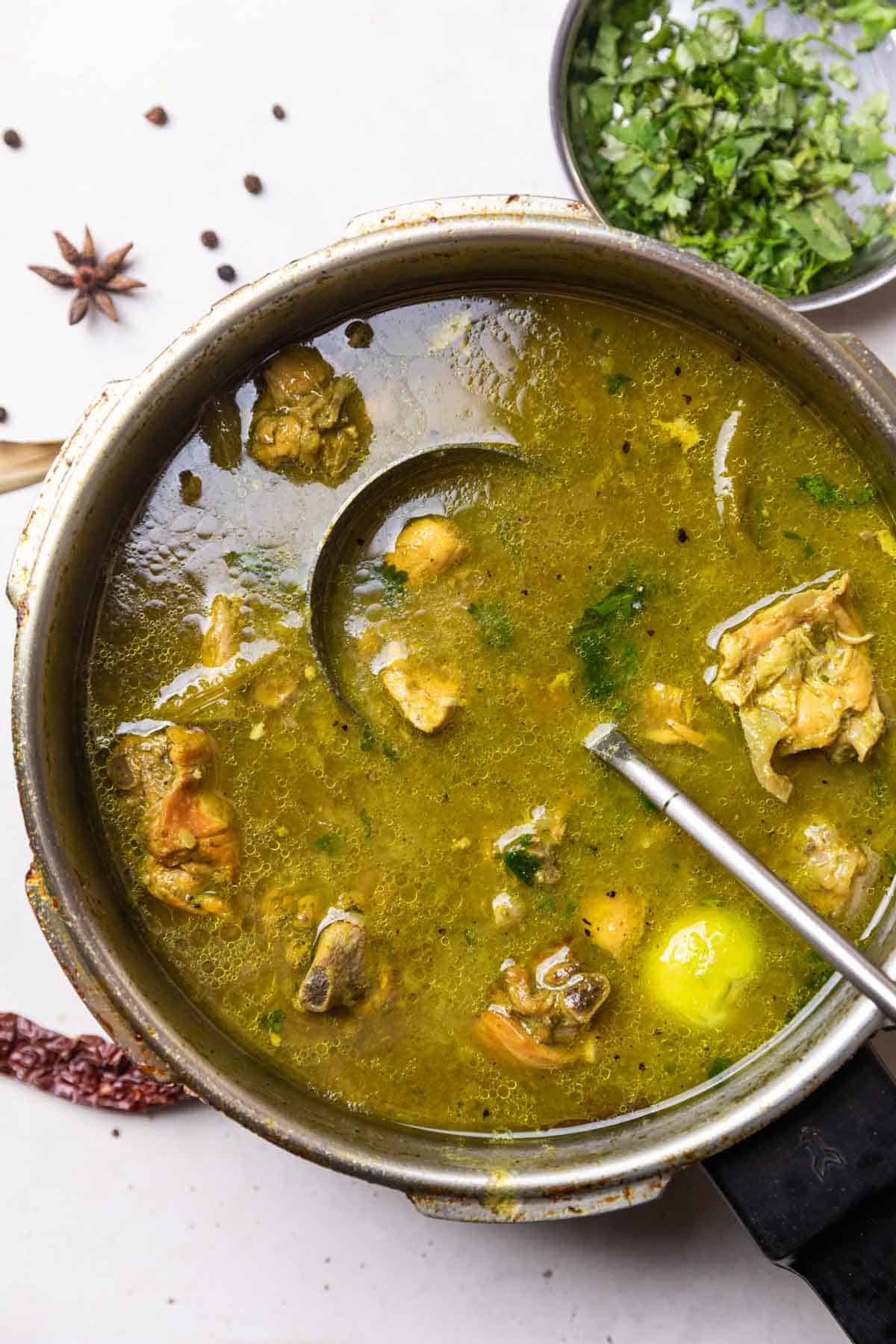 chicken shorba in a pressure cooker with ladle 