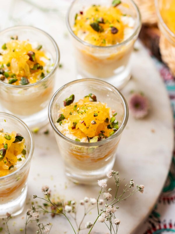 Orange kalakand served in shot glasses and topped with orange segments and chopped nuts