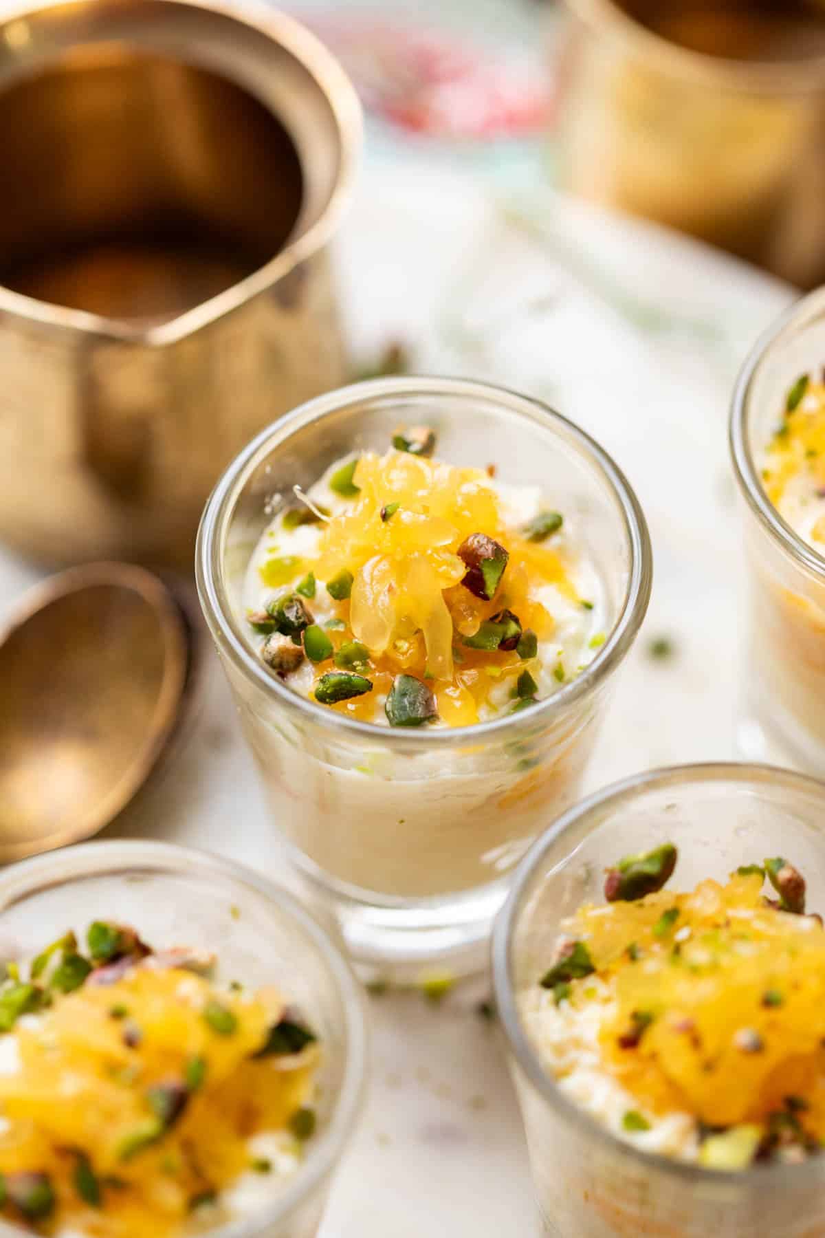 Orange kalakand served in shot glasses and topped with orange separates and chopped nuts