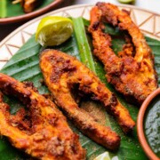 close up of Amritsari fish fry served on a leaf platter with green chutney