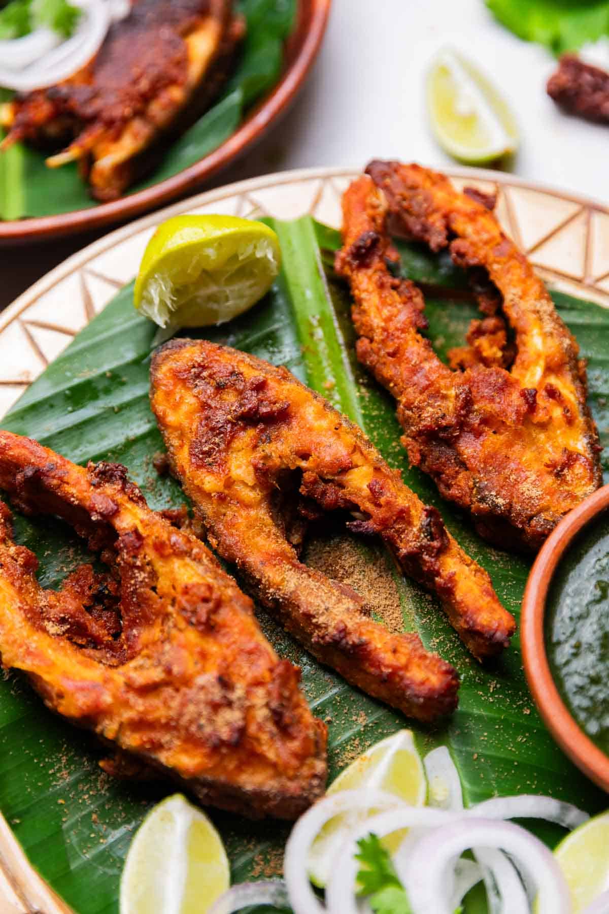 close up of Amritsari fish fry served on a leaf platter with green chutney