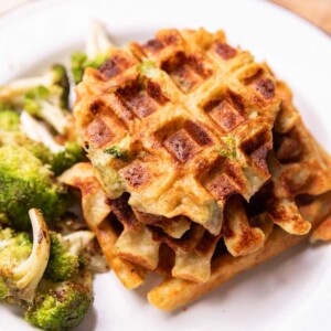broccoli cheese waffles served on a white plate with a side of roasted broccoli