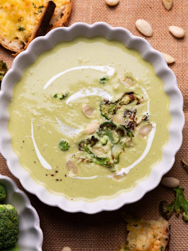broccoli almond soup served in a white bowl with accompaniments