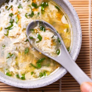 a bowl of egg drop soup with spoon placed on a tablet mat ready to eat