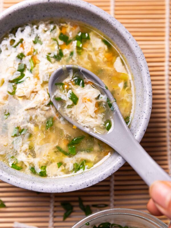 a bowl of egg drop soup with spoon placed on a tablet mat ready to eat