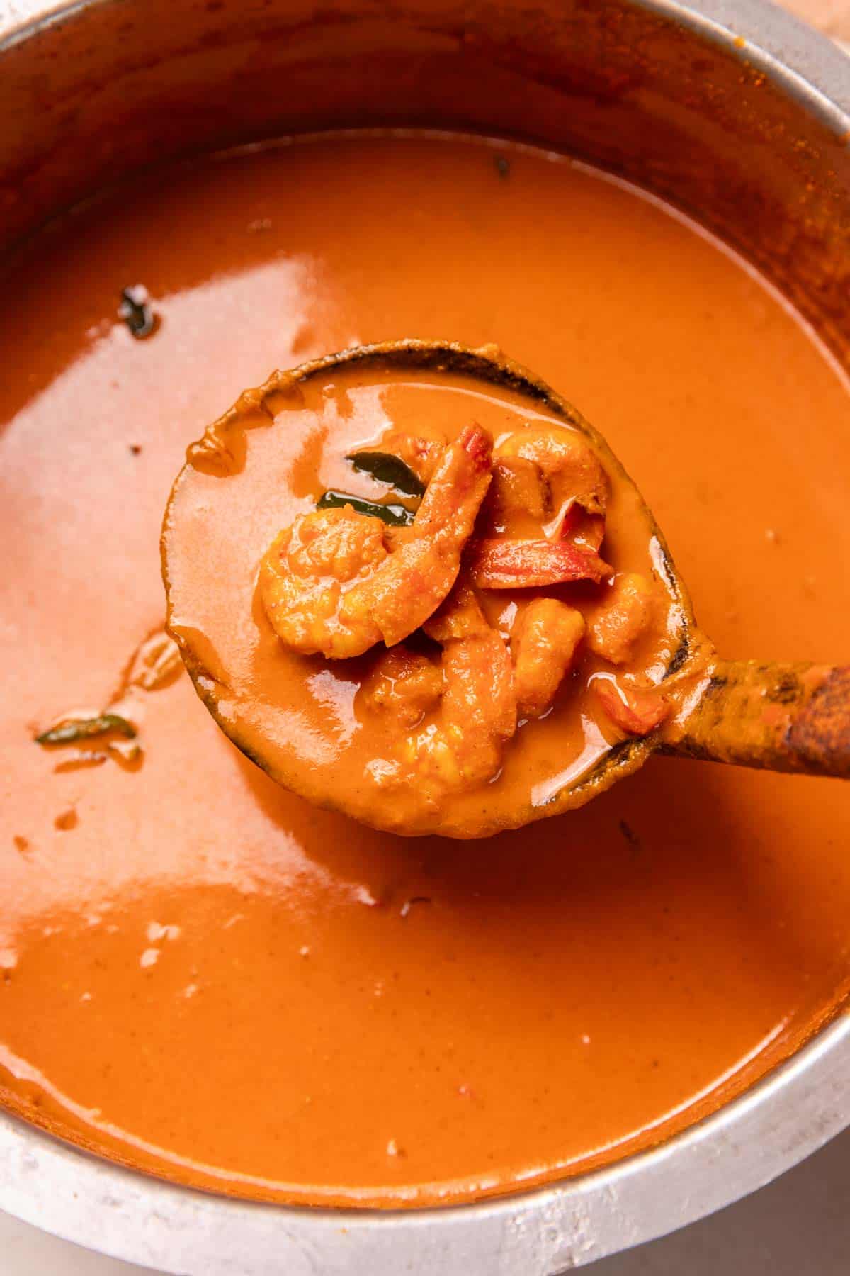 mangalorean prawn curry picked up in a ladle to show the texture