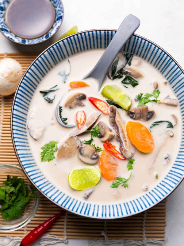 vegetarian tom kha soup served in a bowl with a soup spoon