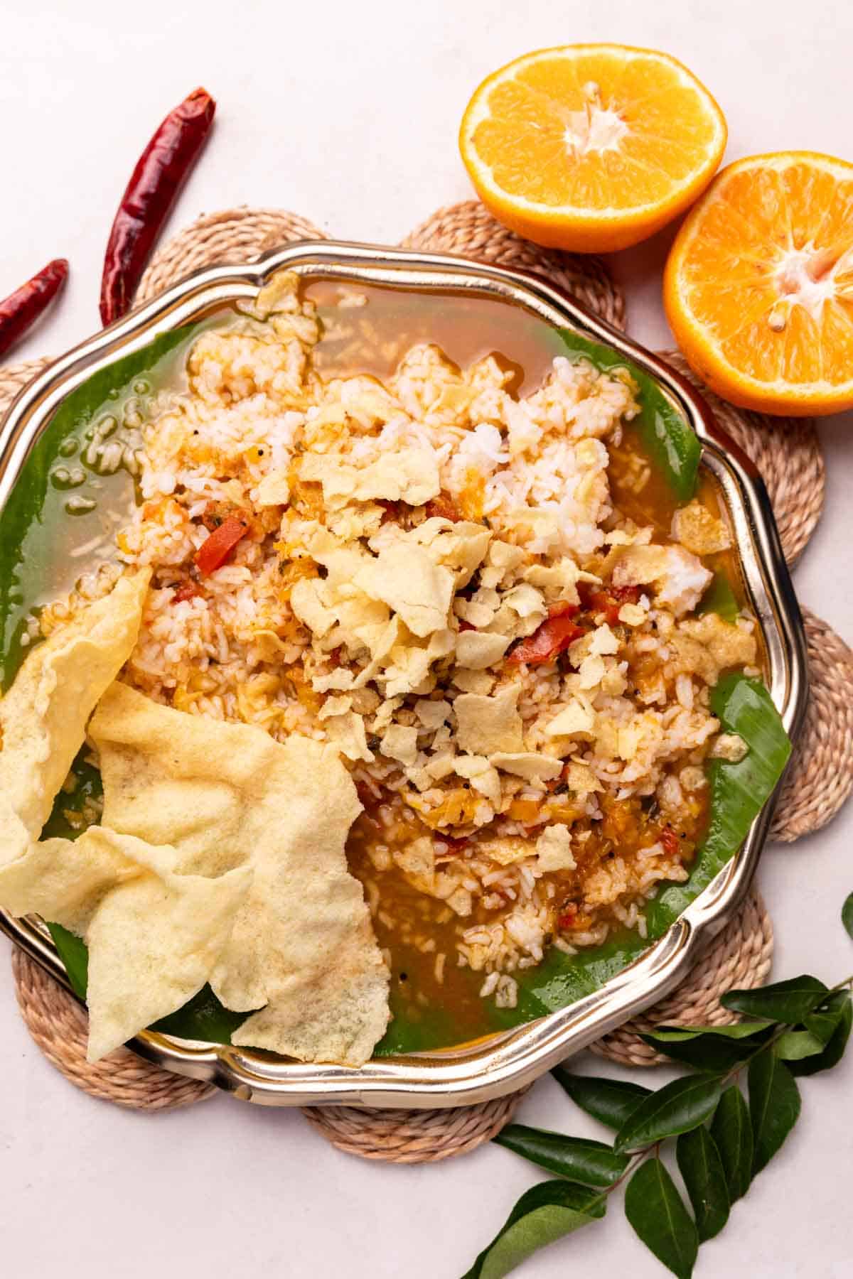 a plate with rice, orange rasam and other accompaniments