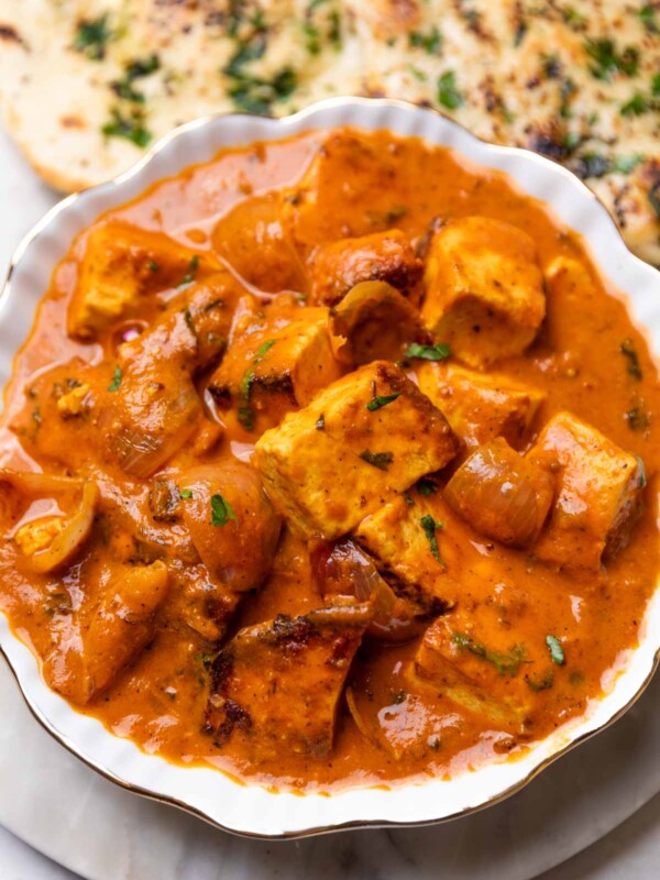 paneer do pyaza served in a white bowl with accompaniments