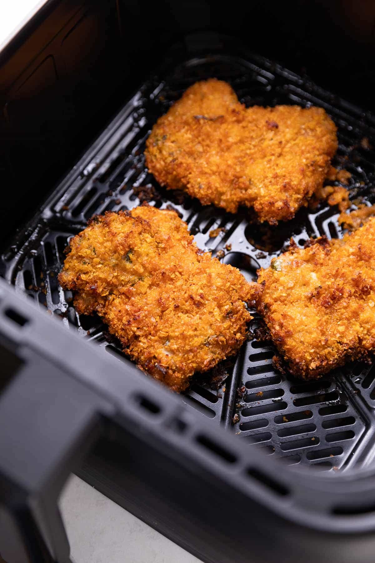fried chicken cooking in an air fryer basket