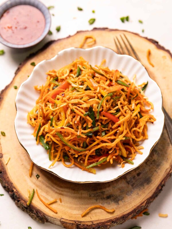 Chinese bhel served in a white bowl with accompaniments