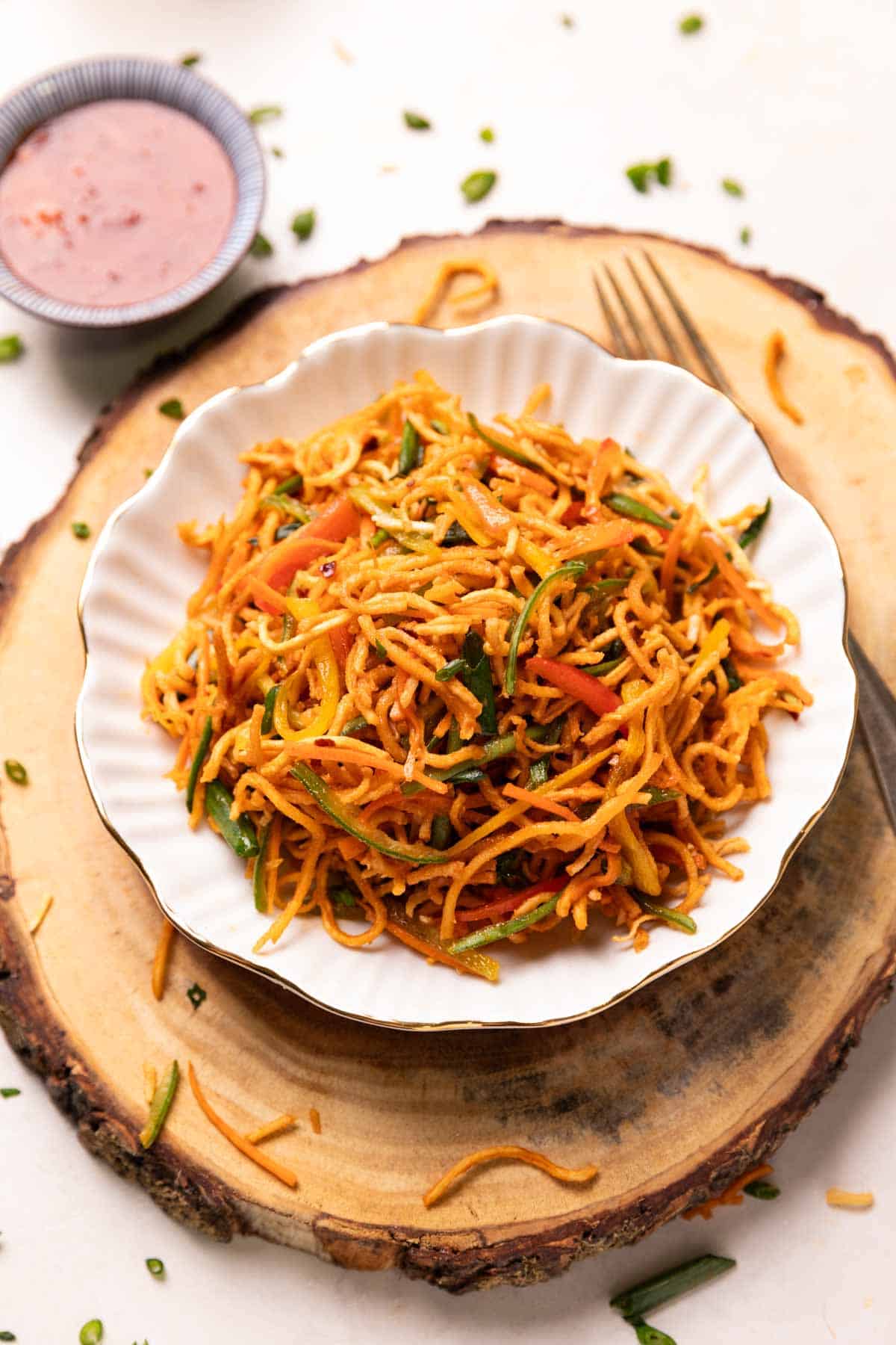 Chinese bhel served in a white bowl with accompaniments