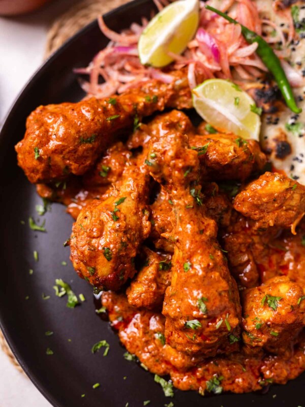 creamy chicken handi served on a black plate with accompaniments