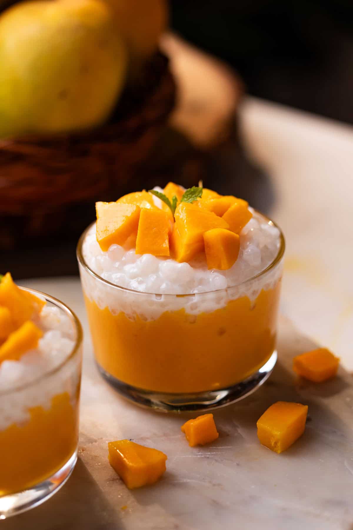 mango sago topped with mango chunks served in a small glass bowls  