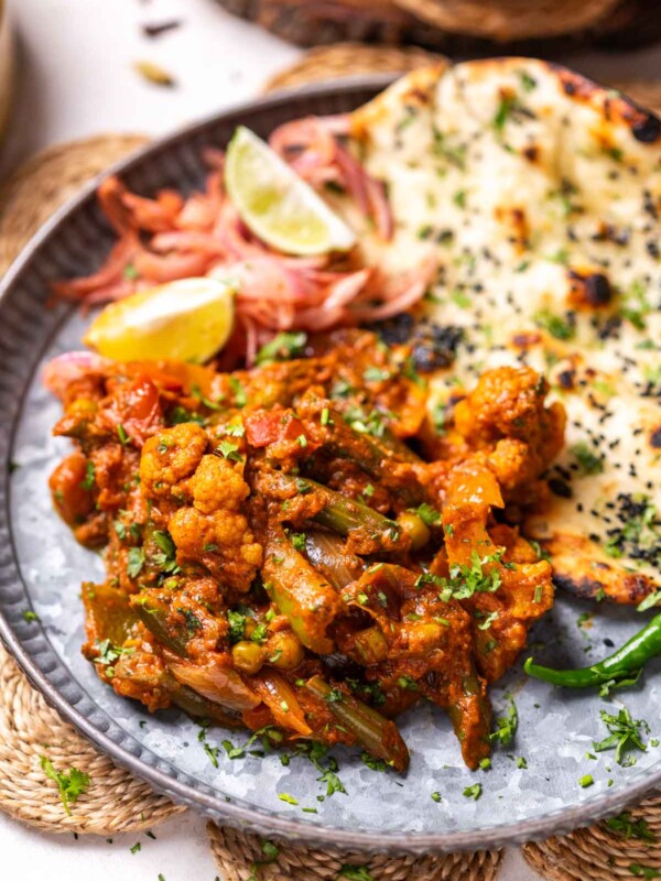 veg kadai served on a platter with naan and onion salad