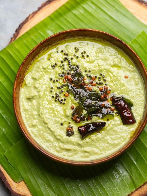 an image of coconut chutney made served in a bowl placed over a banana leaf platter