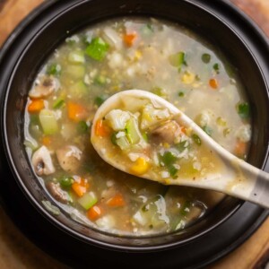 Eight treasure soup served in a black soup bowl with a white soup spoon ready to be eaten