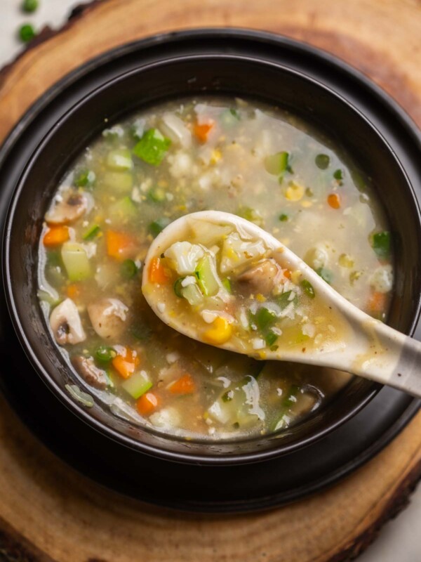 Eight treasure soup served in a black soup bowl with a white soup spoon ready to be eaten