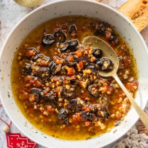 bread dipping oil served in a white bowl with spoon and accompaniments