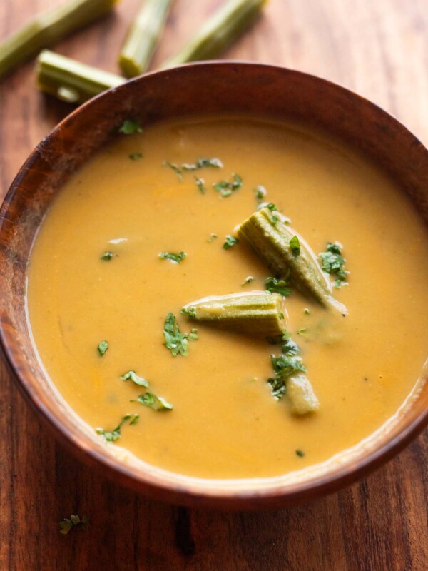 drumstick soup served in a wooden bowl and garnished with boiled drumsticks and coriander leaves