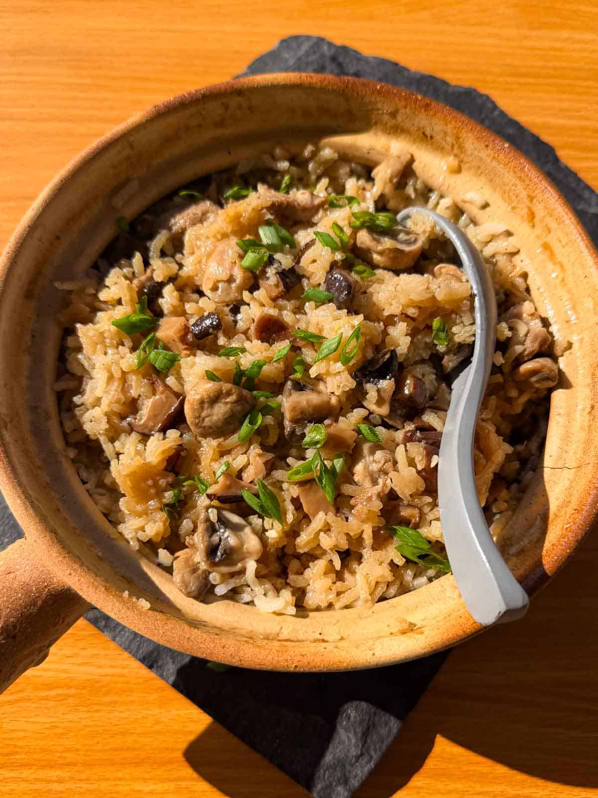 claypot chicken rice with mushroom in the cooking pot with spoon