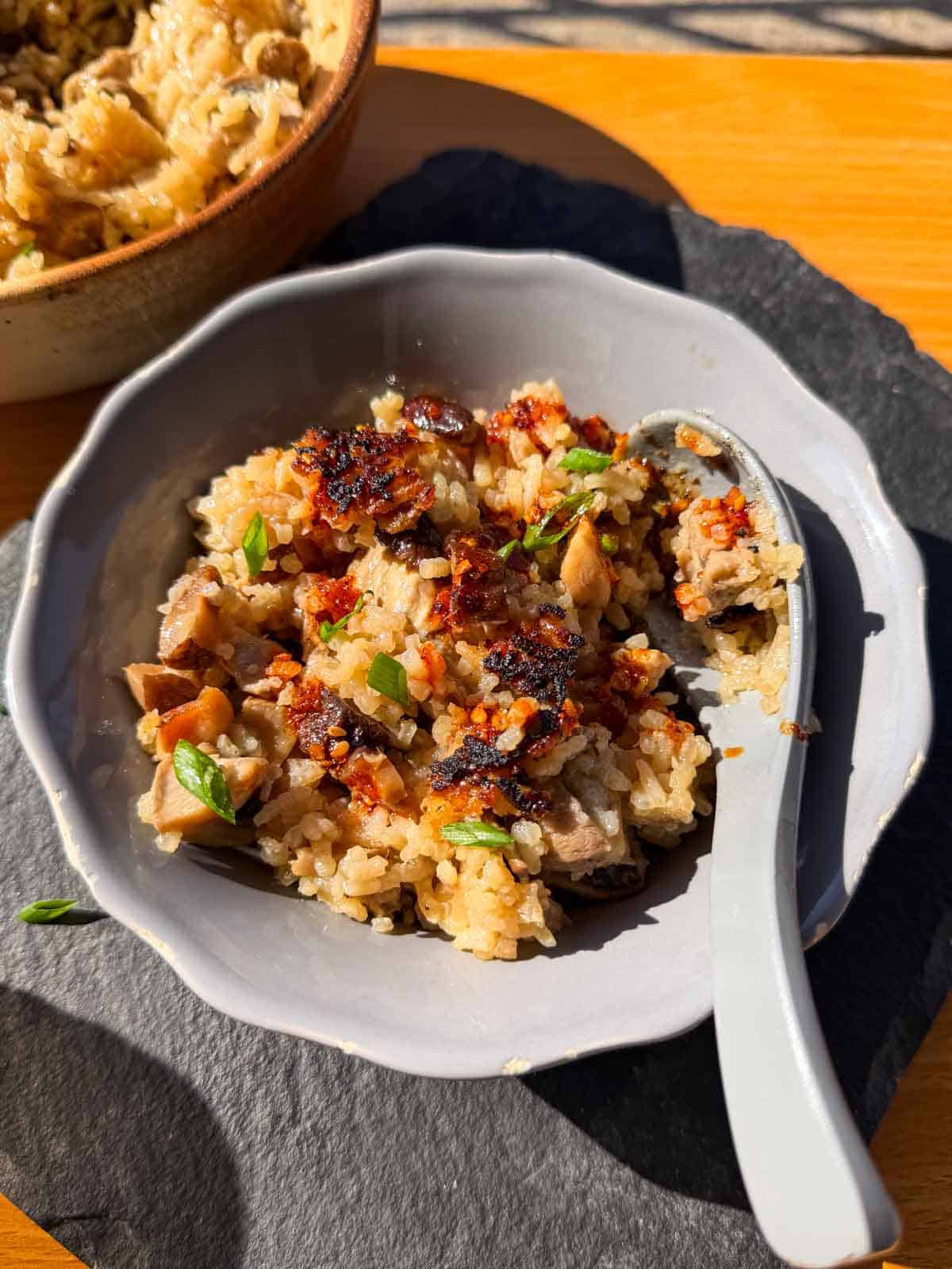 claypot chicken rice with mushroom served in a grey bowl with a spoon