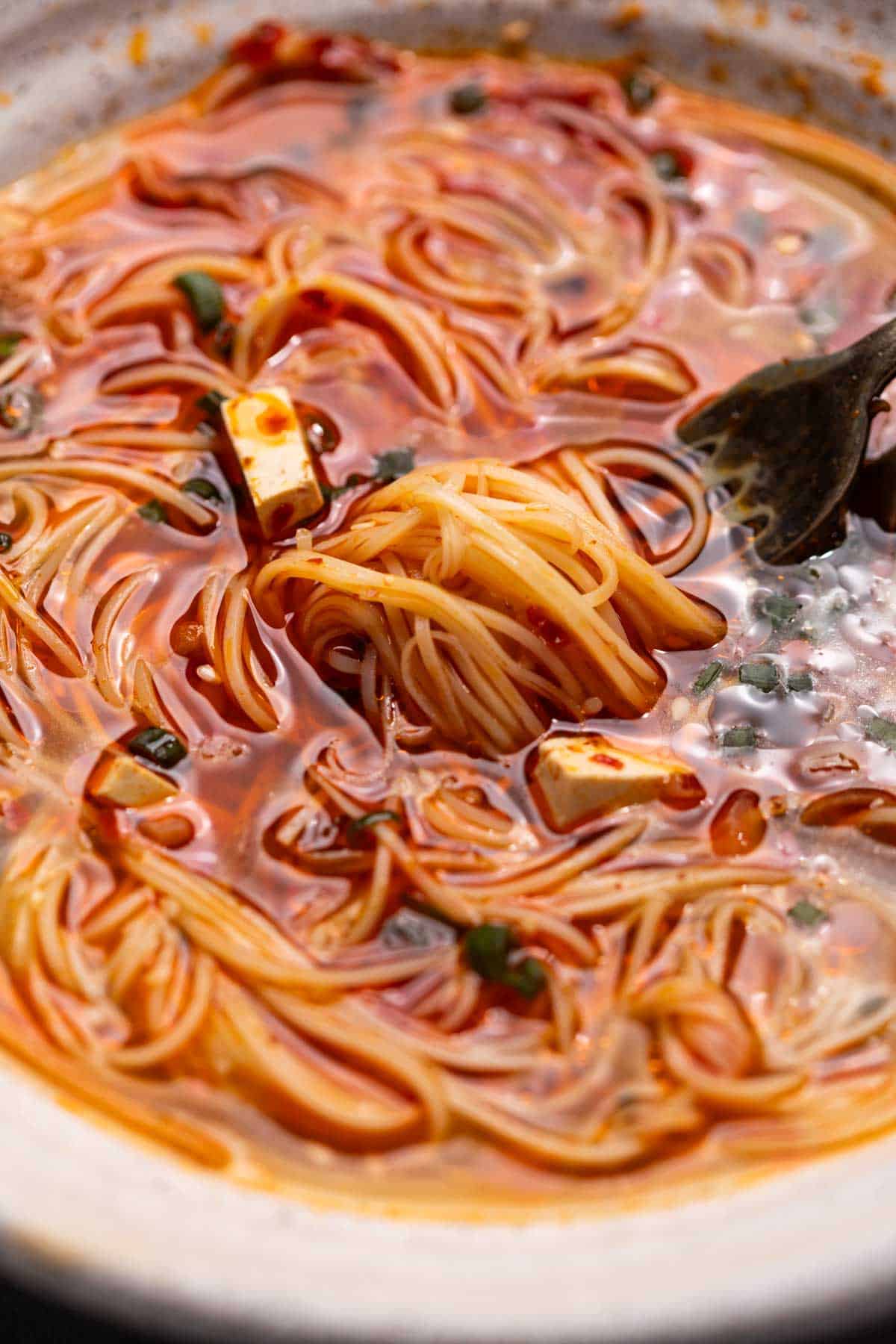 a close up image of spicy noodle soup to show it's consistency and texture
