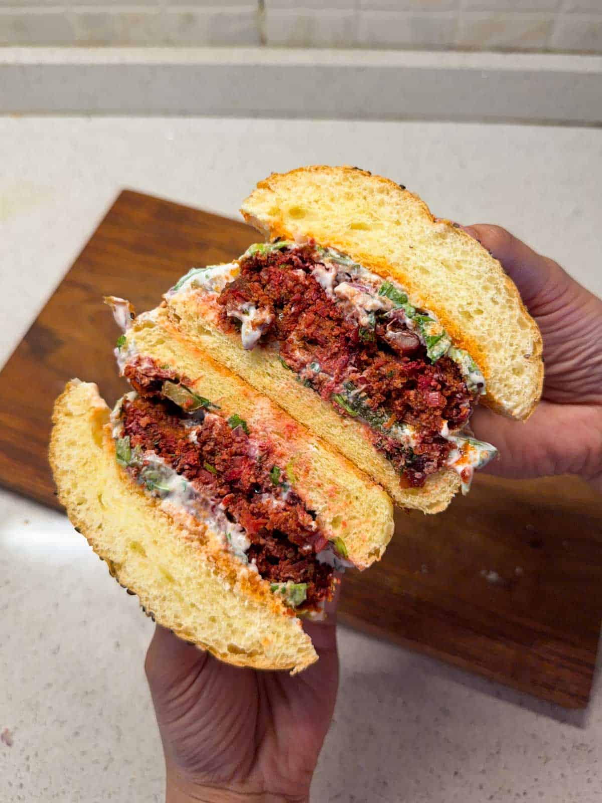 an image of rajma paneer burger cut in half to showcase it's color and texture