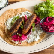 an image of veg seekh kebabs served on a roti with accompaniments